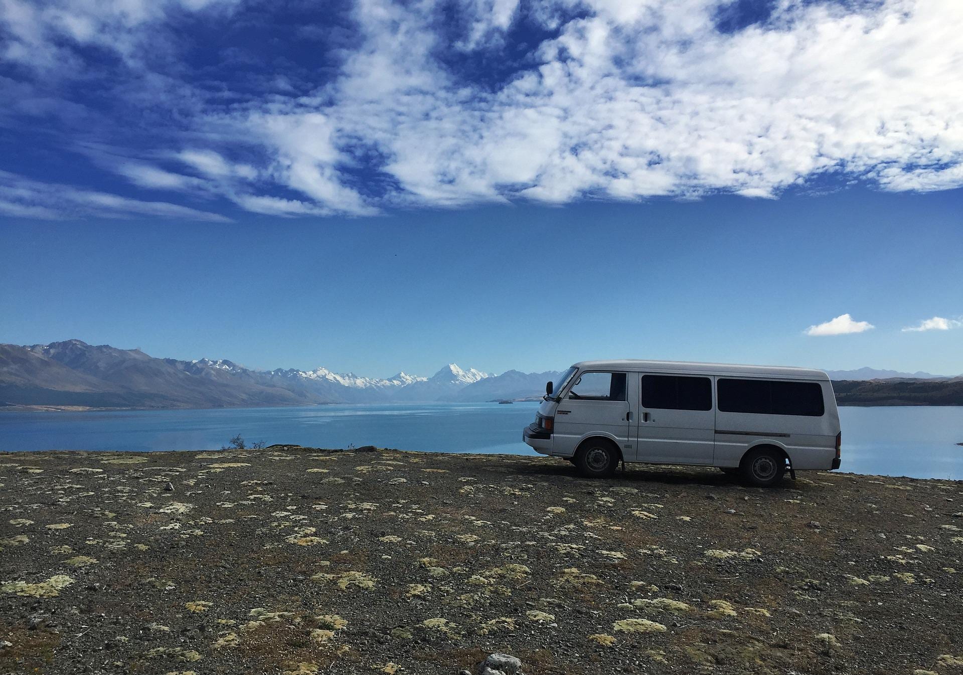 Camper van next to water and mountains