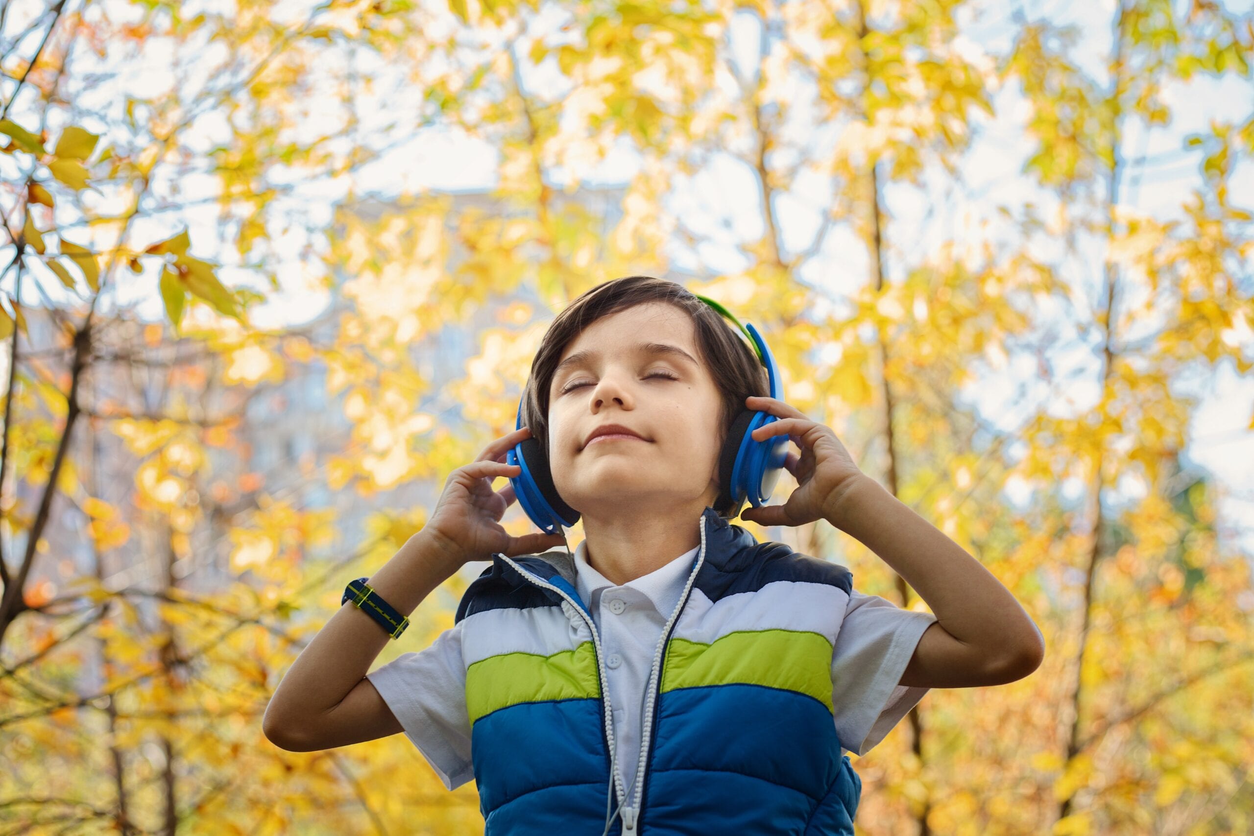 Child listening to podcasts with trees in the background